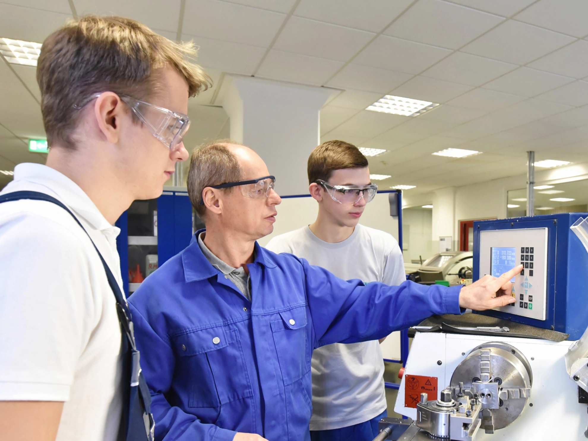 Junge Auszubildende in der technischen Berufsausbildung werden von älteren Trainer auf CNC-Drehmaschinen Maschinen unterrichtet